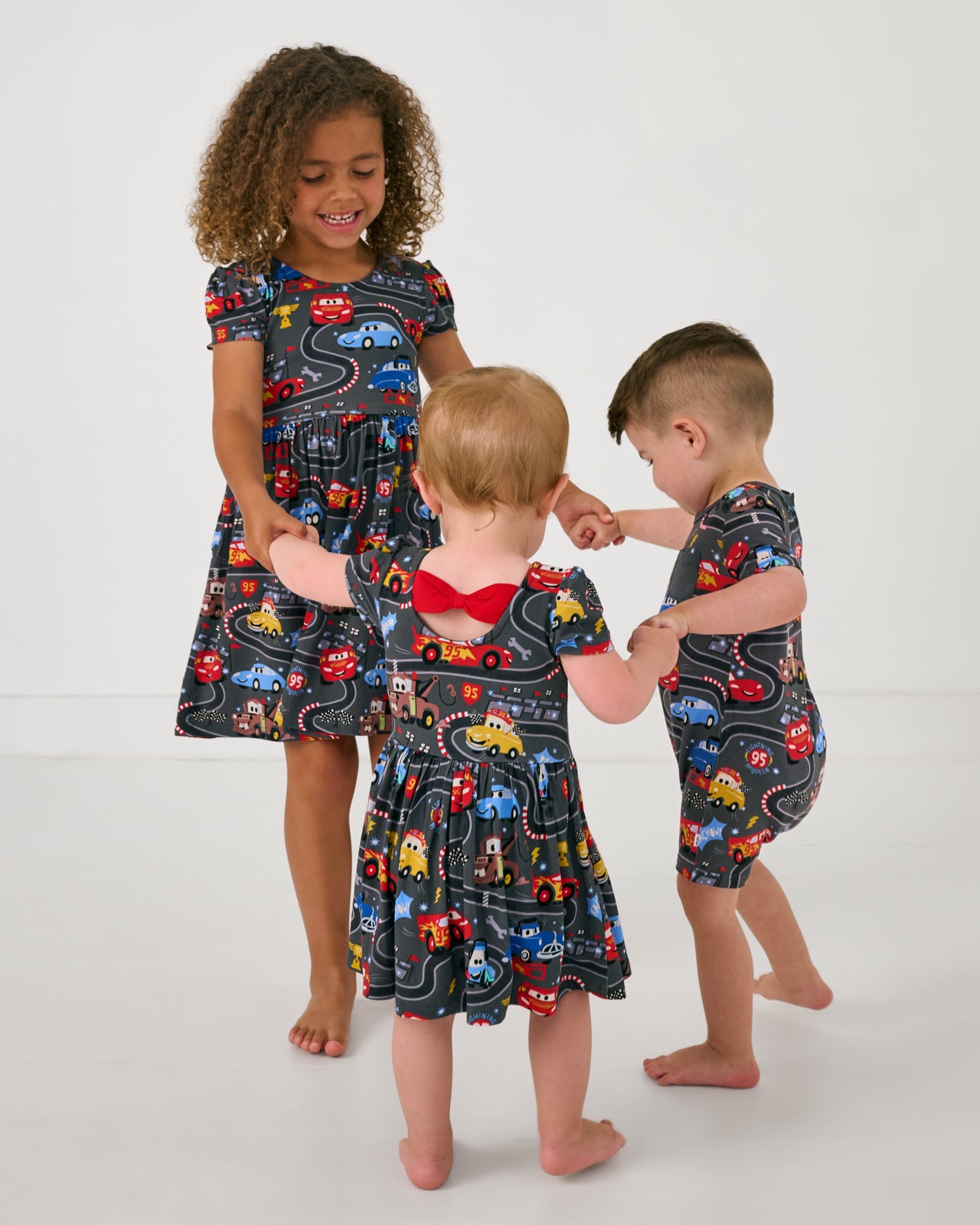 Three children wearing matching Disney & Pixar Piston Cup print styles