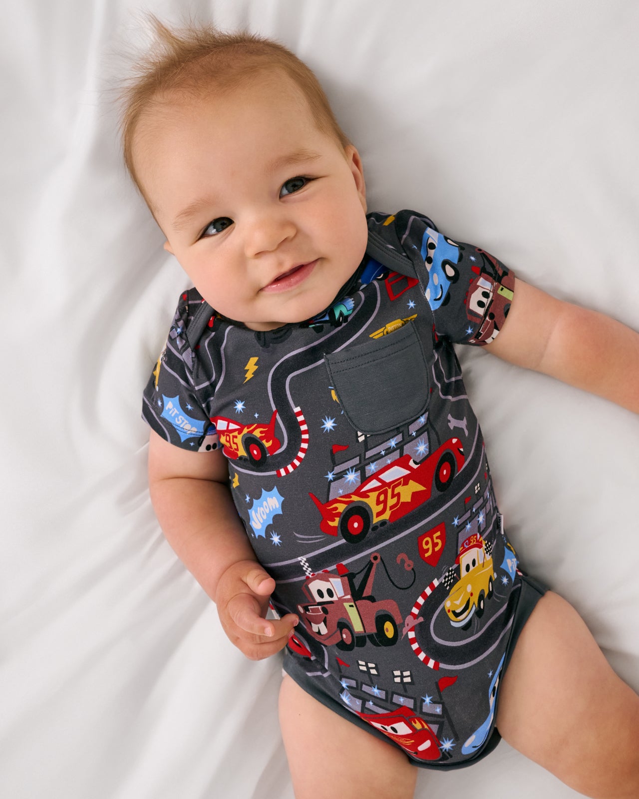 Aerial view of baby wearing the Disney & Pixar Piston Cup Pocket Bodysuit