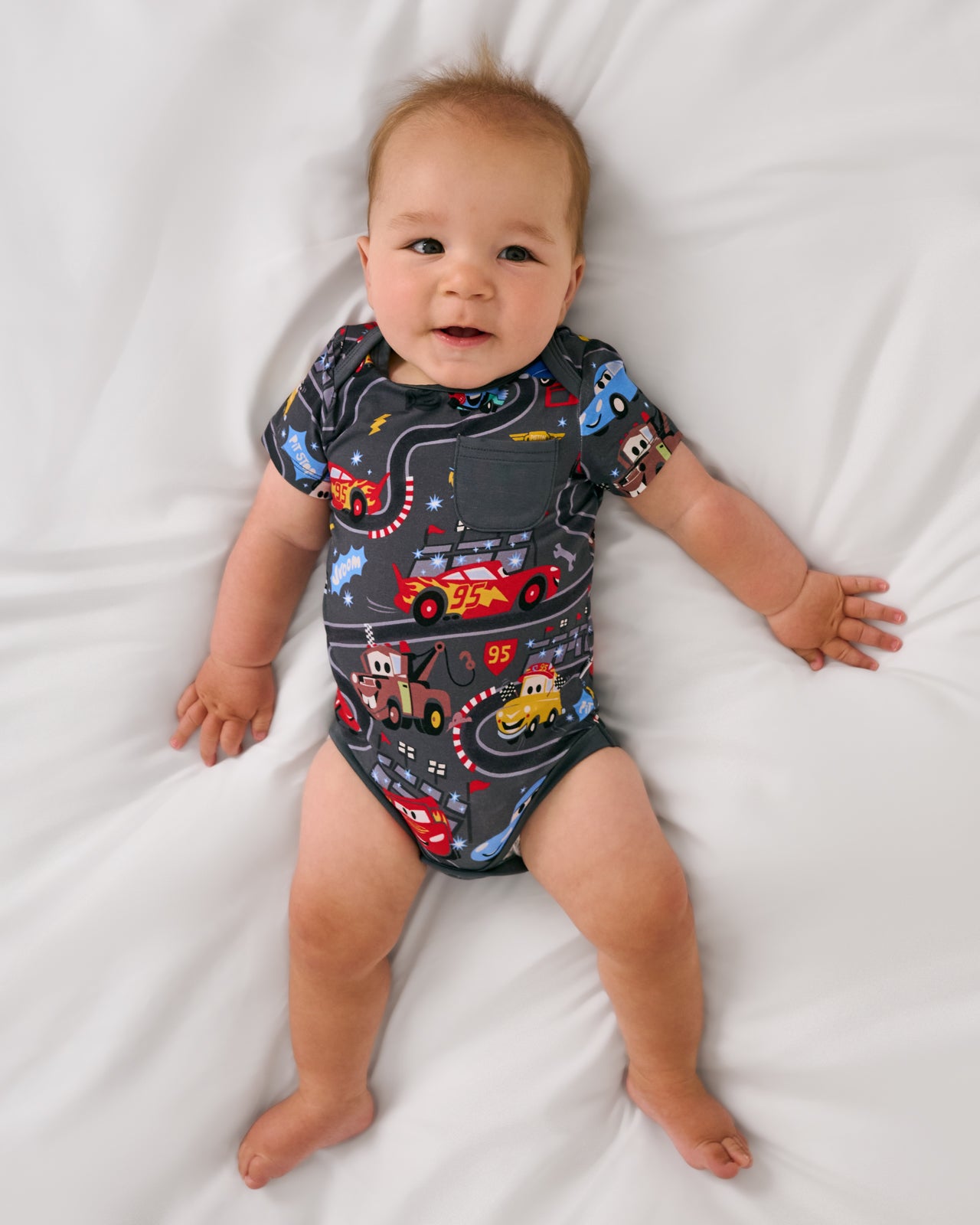 Alternate aerial view of baby wearing the Disney & Pixar Piston Cup Pocket Bodysuit