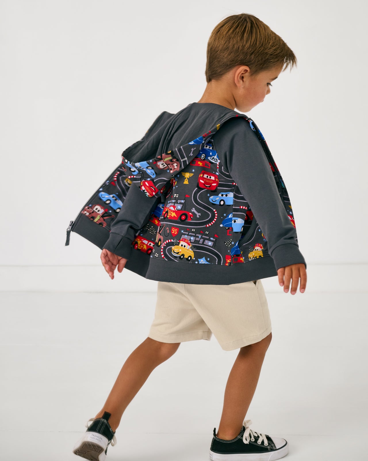 Child in motion wearing the Disney & Pixar Piston Cup Zip Hoodie layered over the Cars themed tee
