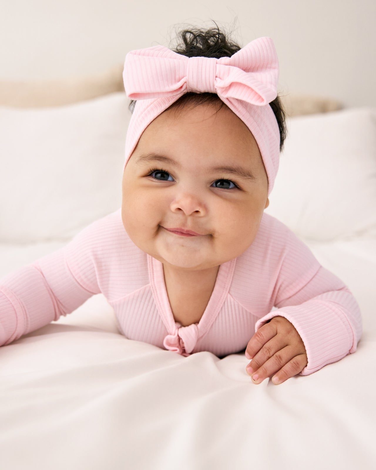 Newborn wearing the Prima Pink Ribbed Luxe Bow Headband with a matching zipper pajama