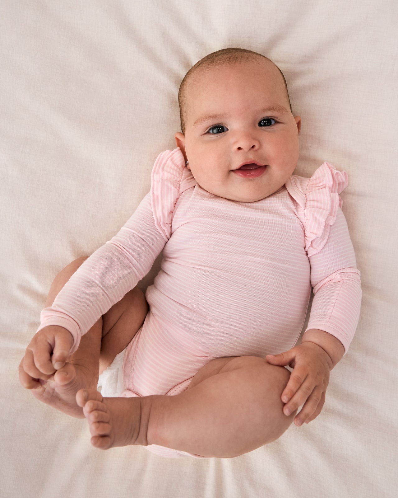 Aerial view of baby wearing the Prima Pink Stripe Flutter Bodysuit