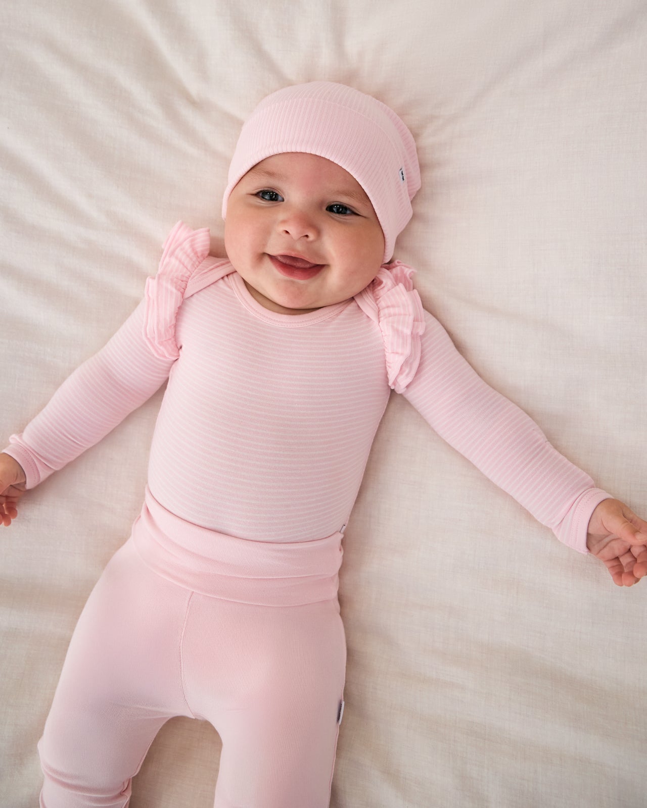 Aerial view of baby wearing the Prima Pink Fold-Over Legging with a matching pink infant beanie