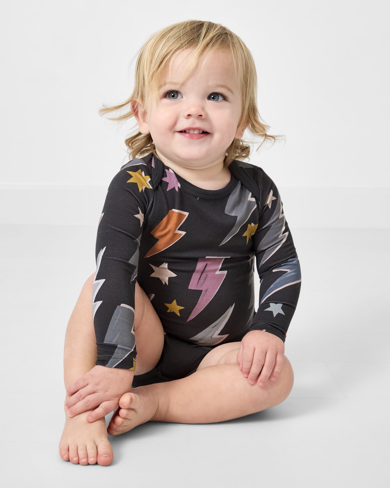 Sitting baby wearing the Rad Bolts Bodysuit on a white background