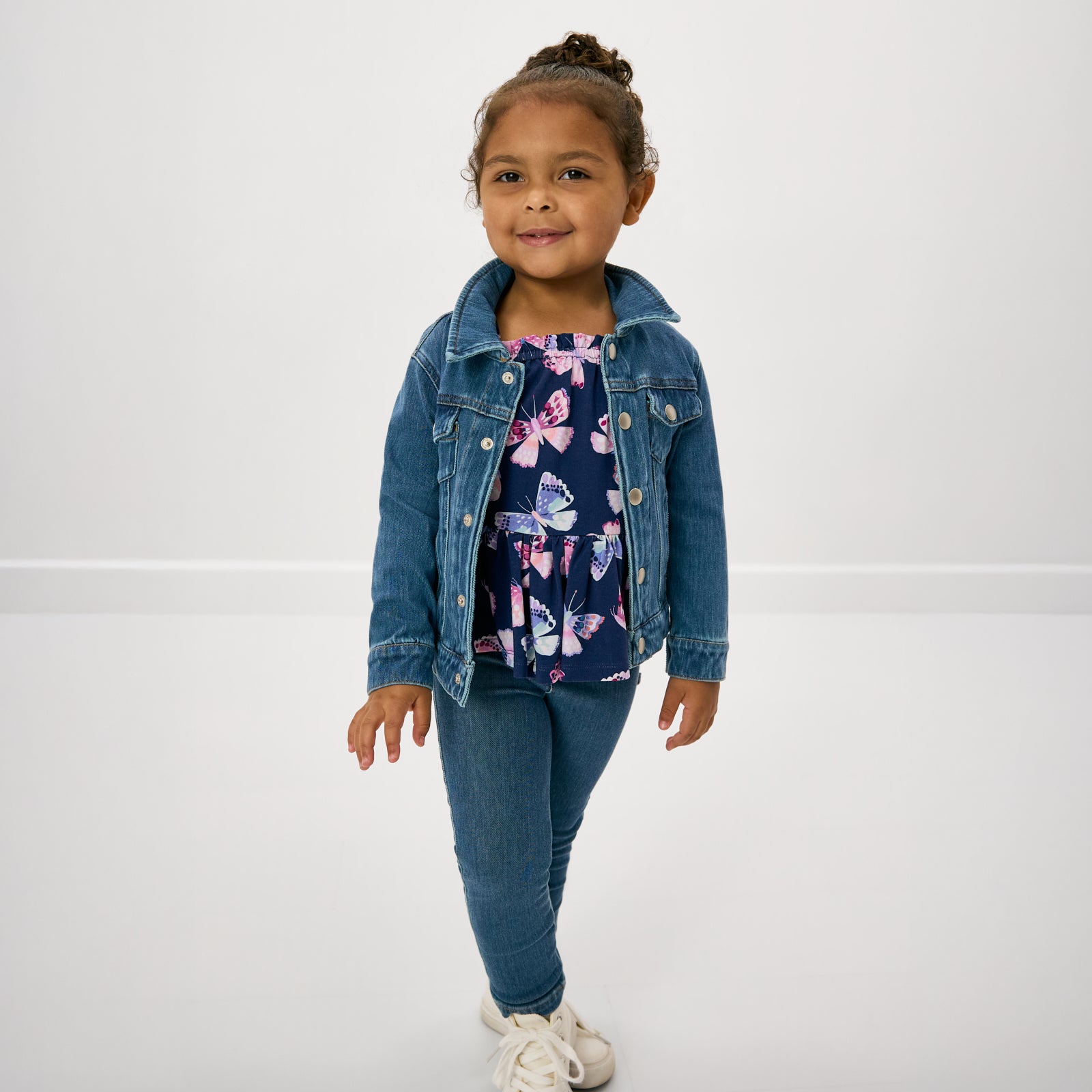 Girl wearing the Royal Butterflies Peplum Flutter Tank layered under a blue jean jacket