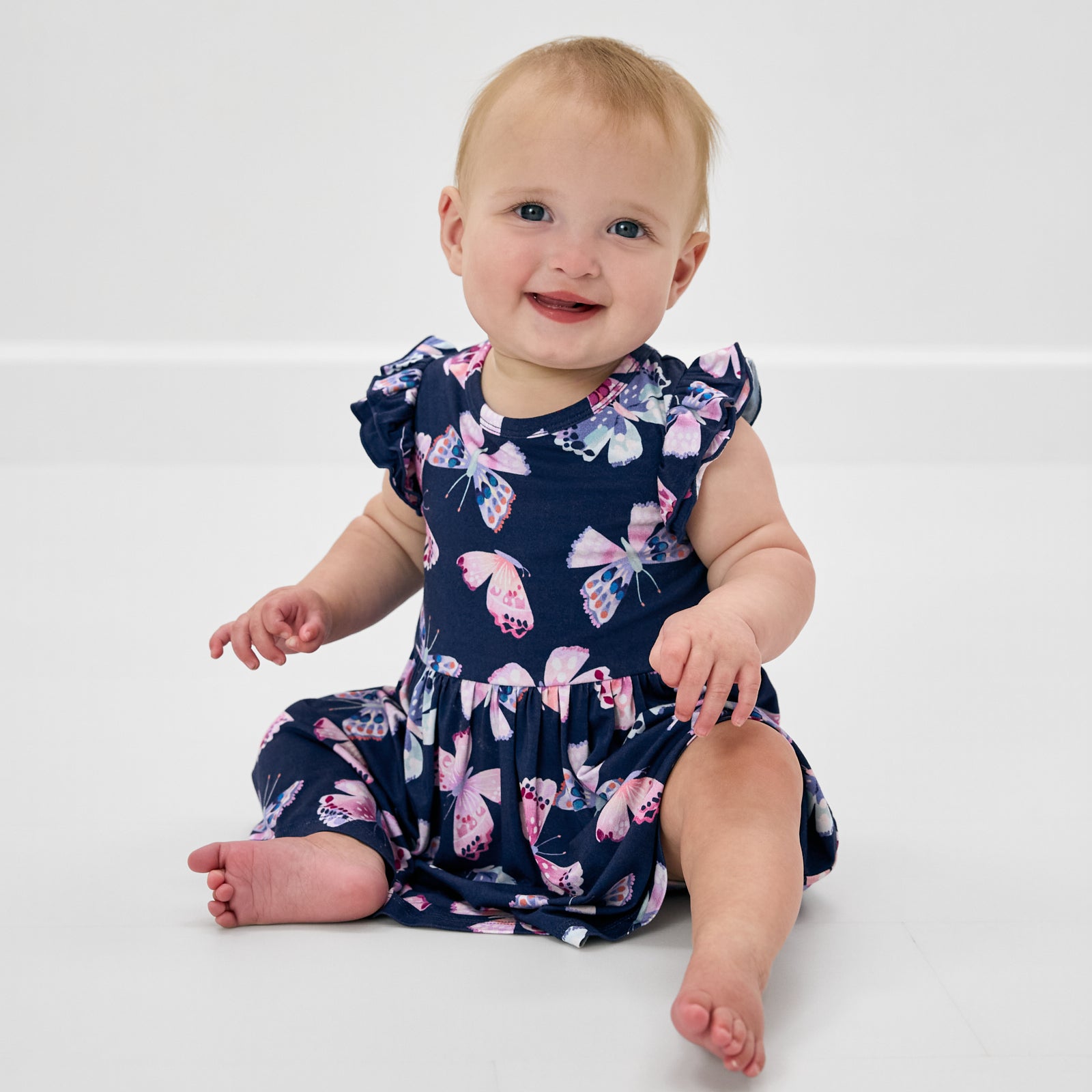 Sitting baby wearing the Royal Butterflies Flutter Twirl Dress with Bodysuit