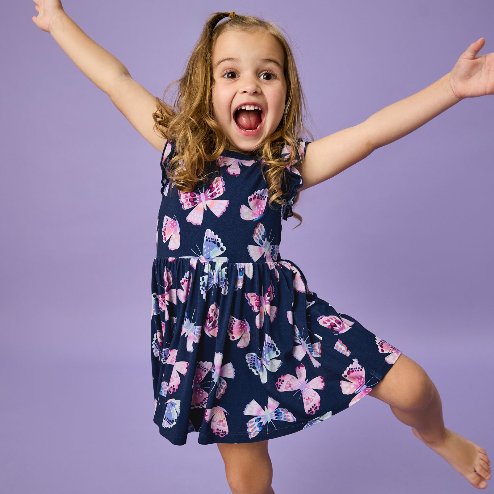 Girl wearing a butterfly print dress on a purple background