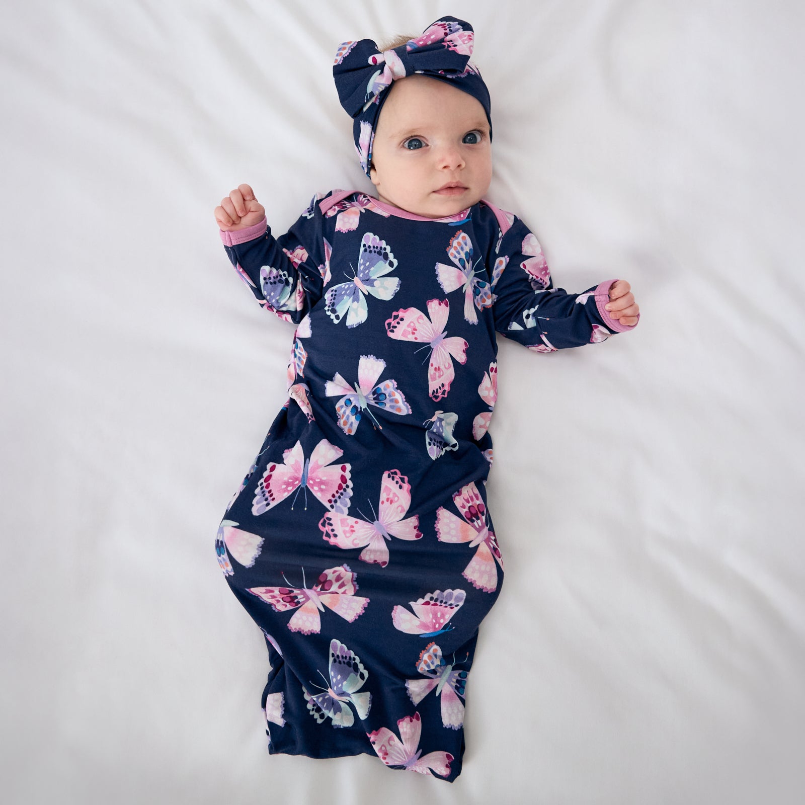 Aerial view of baby wearing the Royal Butterflies Luxe Bow Headband and matching infant gown