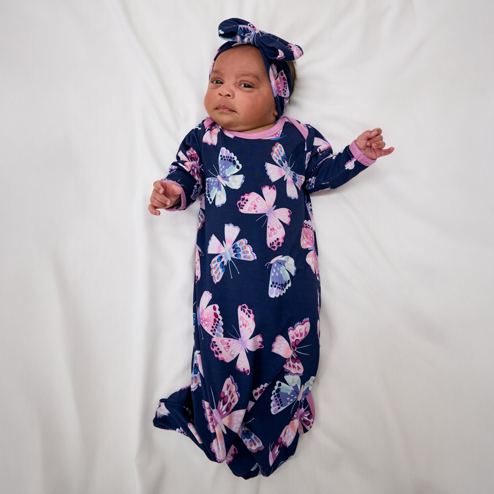 Aerial view of baby wearing the Royal Butterflies Infant Gown and matching bow headband