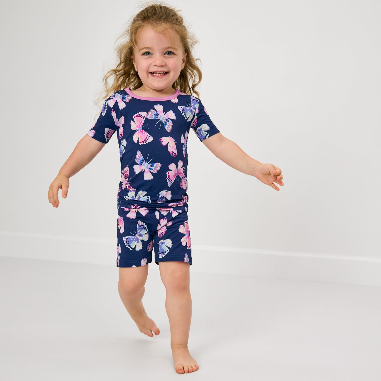 Walking child wearing the Royal Butterflies Two-Piece Short Sleeve & Shorts Pajama Set