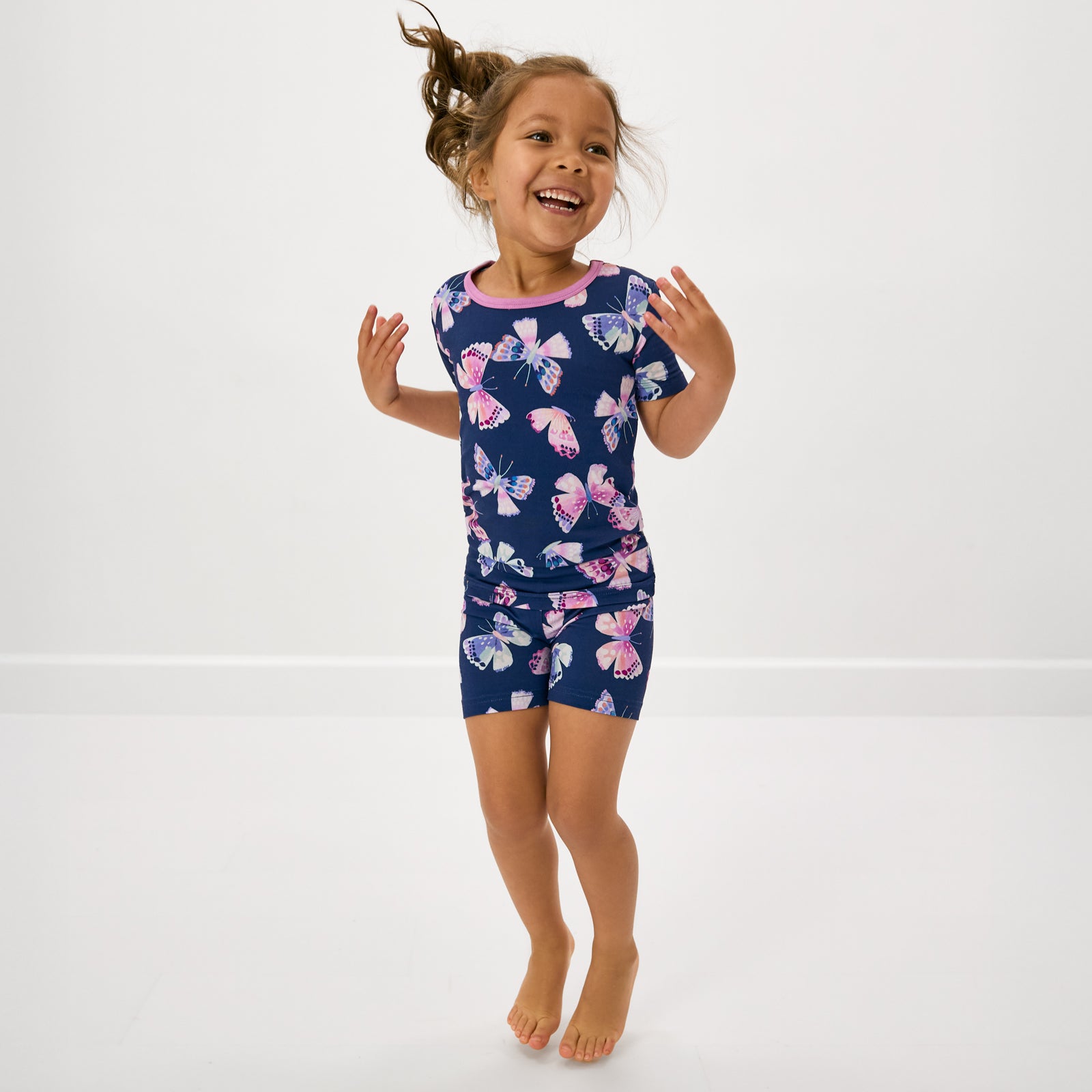 Jumping girl wearing the Royal Butterflies Two-Piece Short Sleeve & Shorts Pajama Set