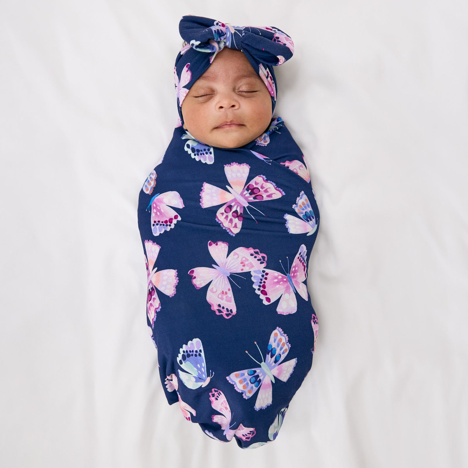Aerial view of baby wearing the Royal Butterflies Swaddle & Luxe Bow Headband Set