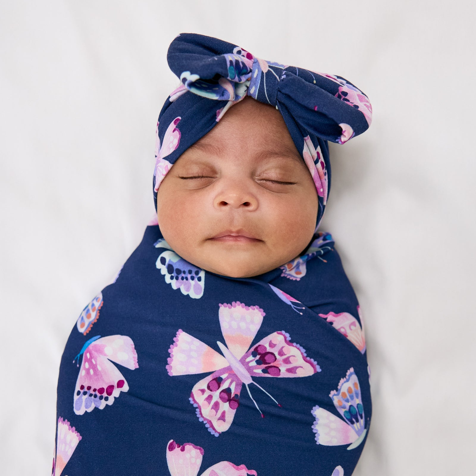Close up of baby wearing the Royal Butterflies Swaddle & Luxe Bow Headband Set