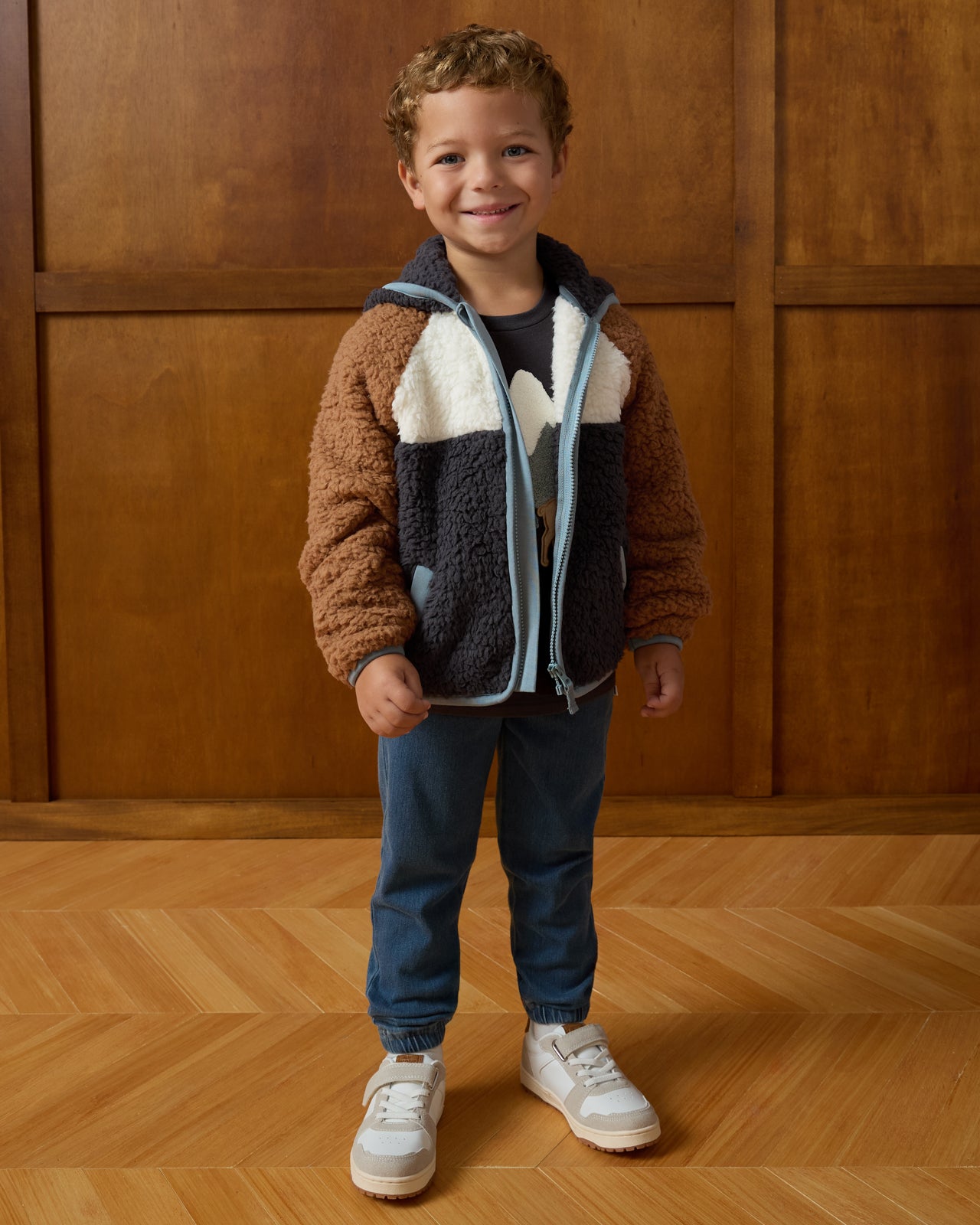 Child wearing the Shadow Gray Sherpa Jacket on a brown background
