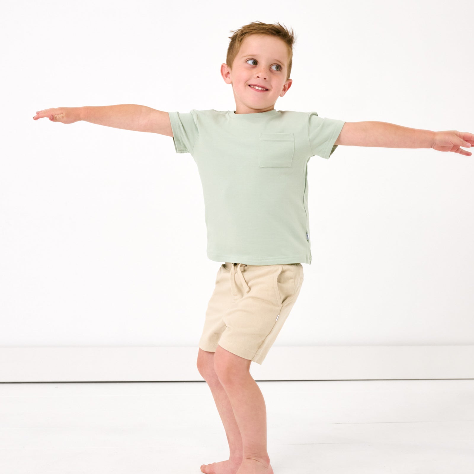 Posing child wearing the Sage Mist Relaxed Pocket Tee