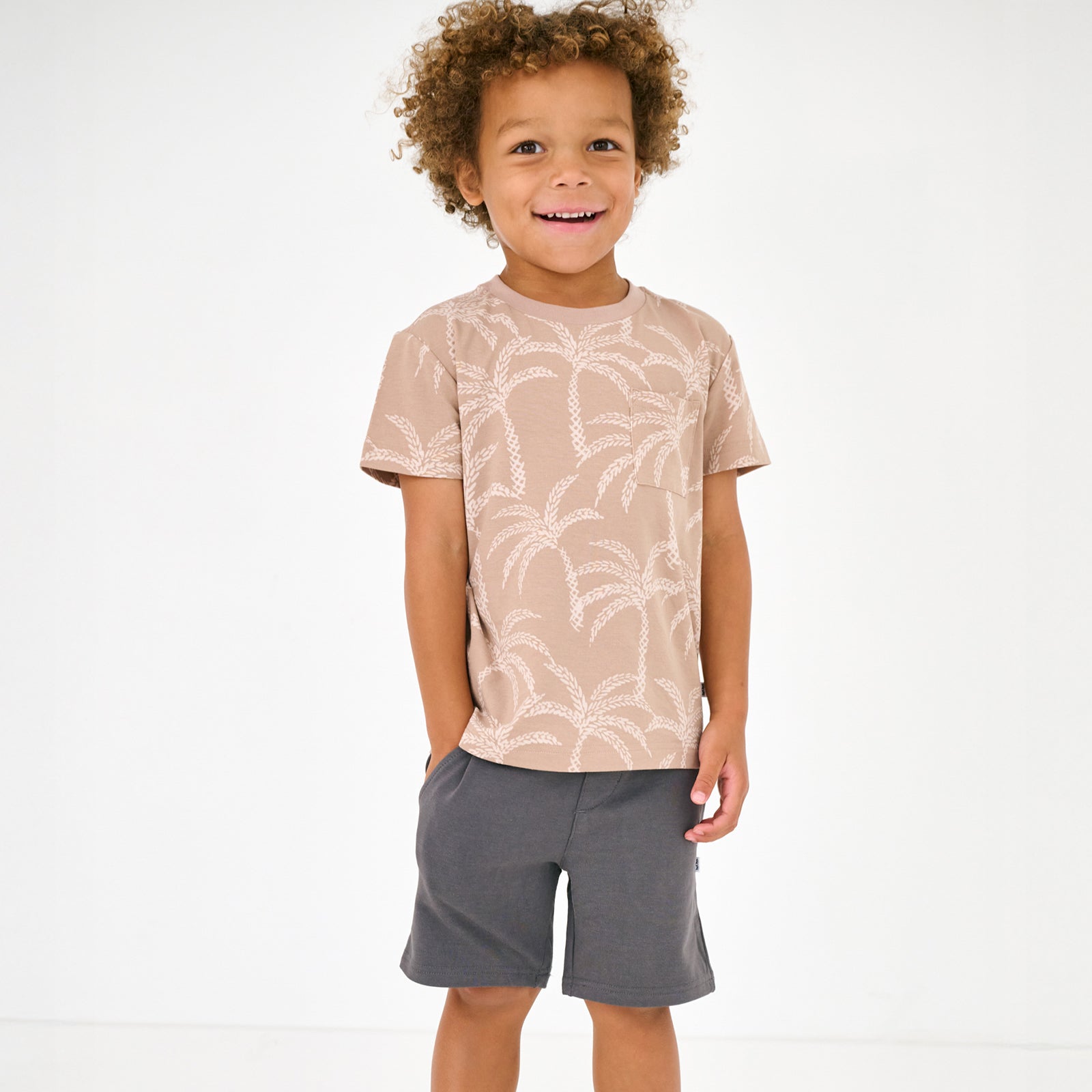 Standing child wearing the Washed Black Drawstring Shorts with the Sandy Palms tee