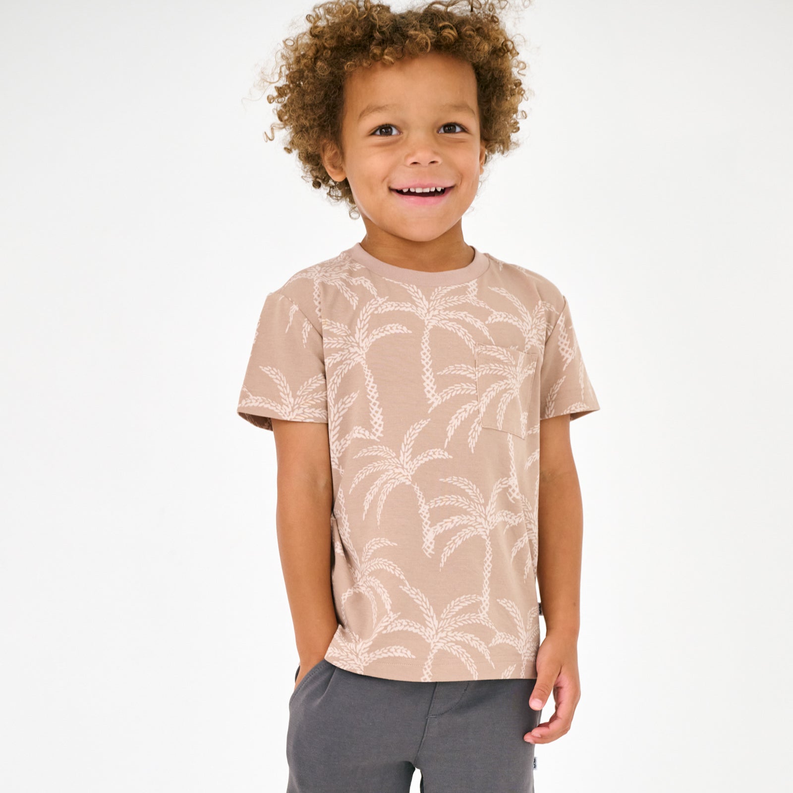 Standing child wearing the Sandy Palms Relaxed Pocket Tee with washed black shorts