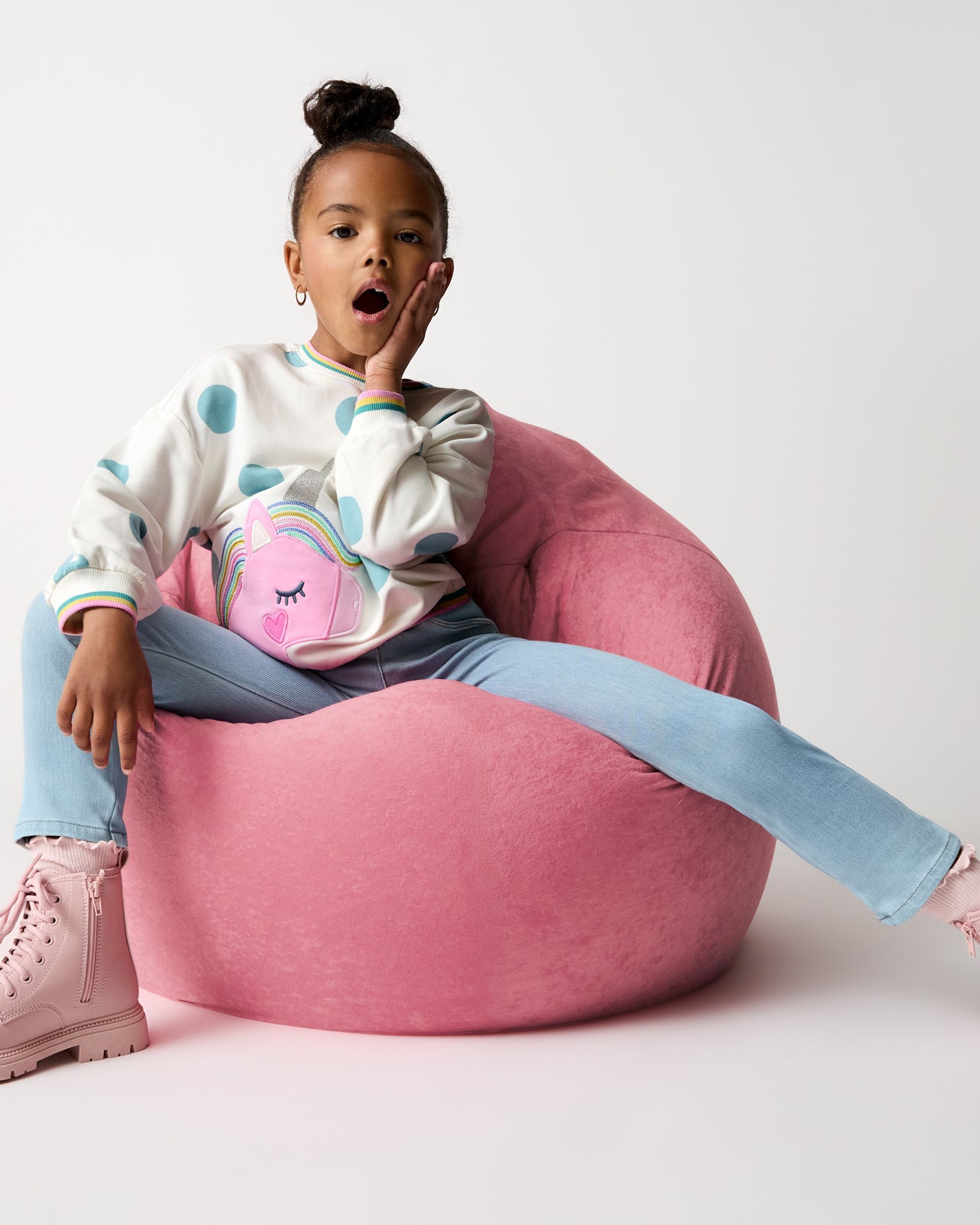 Grl on a pink bean bag chair wearing the Unicorn Drop Shoulder Crewneck