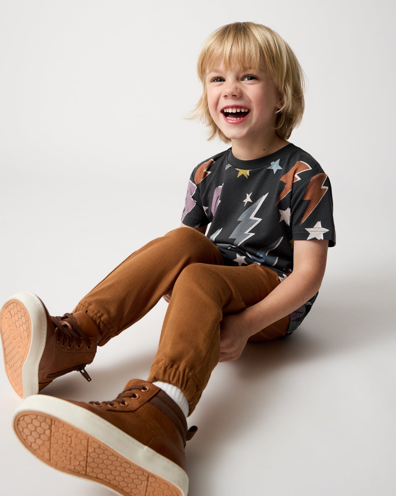 Sitting child wearing the Rad Bolts Relaxed Tee with Rich Toffee Denim Jogger