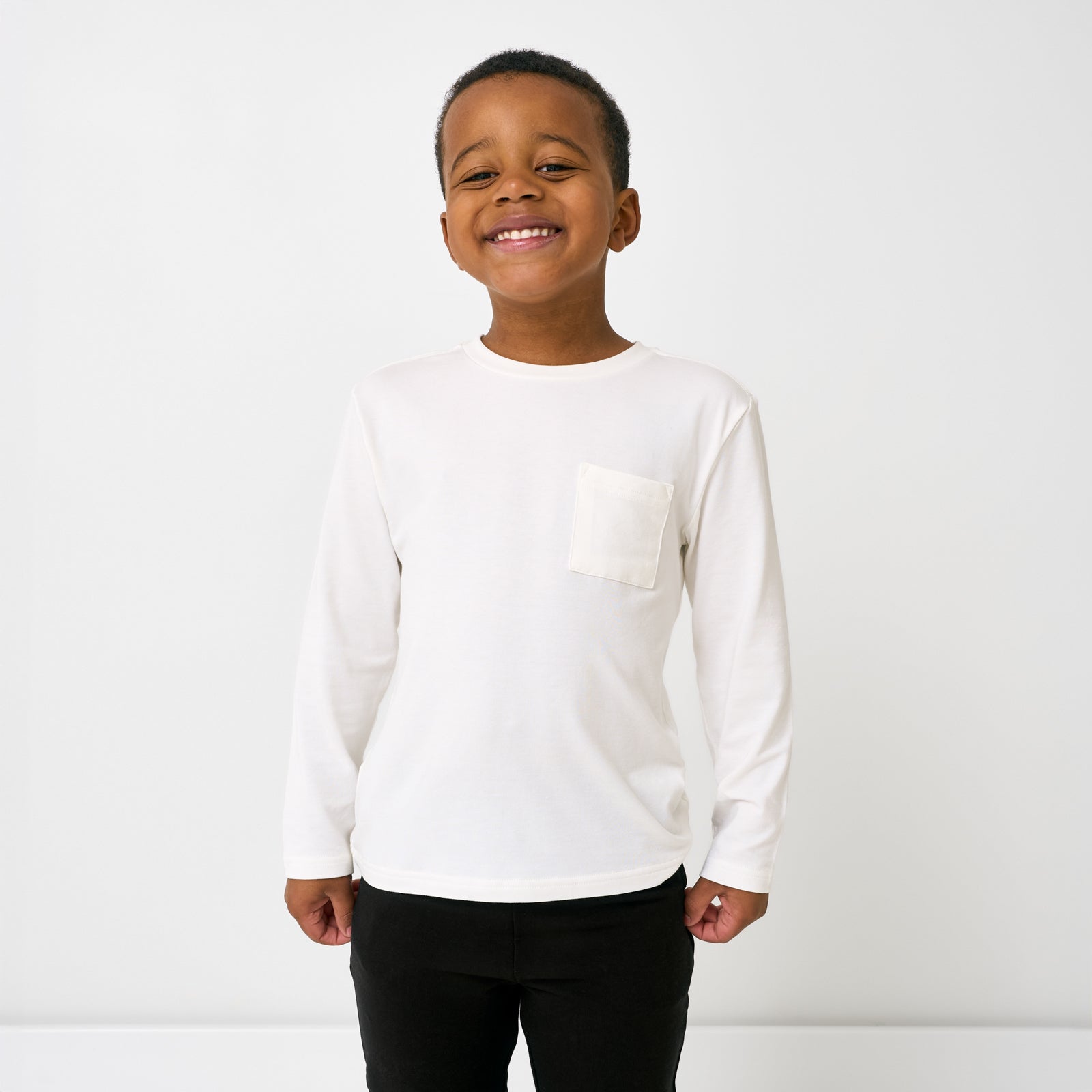 Standing boy wearing the Soft White Long Sleeve Relaxed Pocket Tee