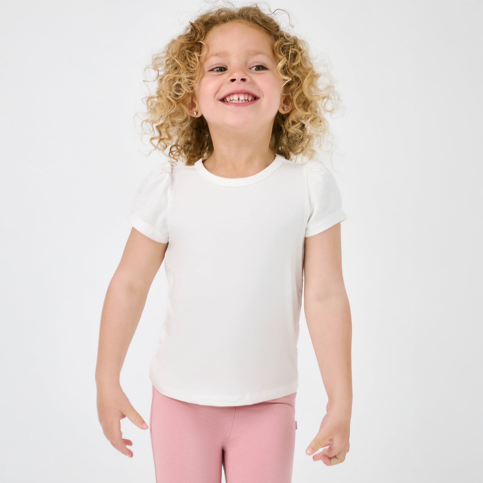 Standing child wearing the Soft White Puff Sleeve Tee with mauve blush leggings