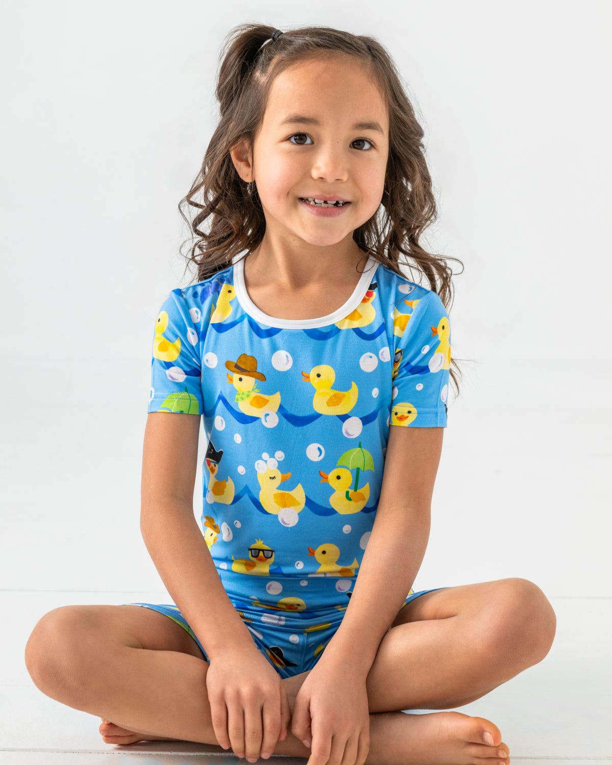 Sitting girl wearing the Splish Splash Two-Piece Short Sleeve & Shorts Pajama Set