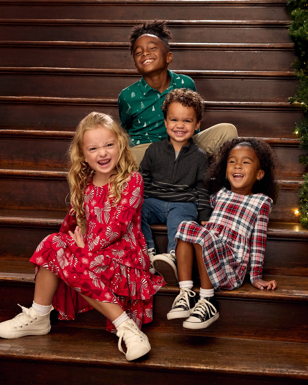 Group of four children on a staircase wearing Holiday Play styles
