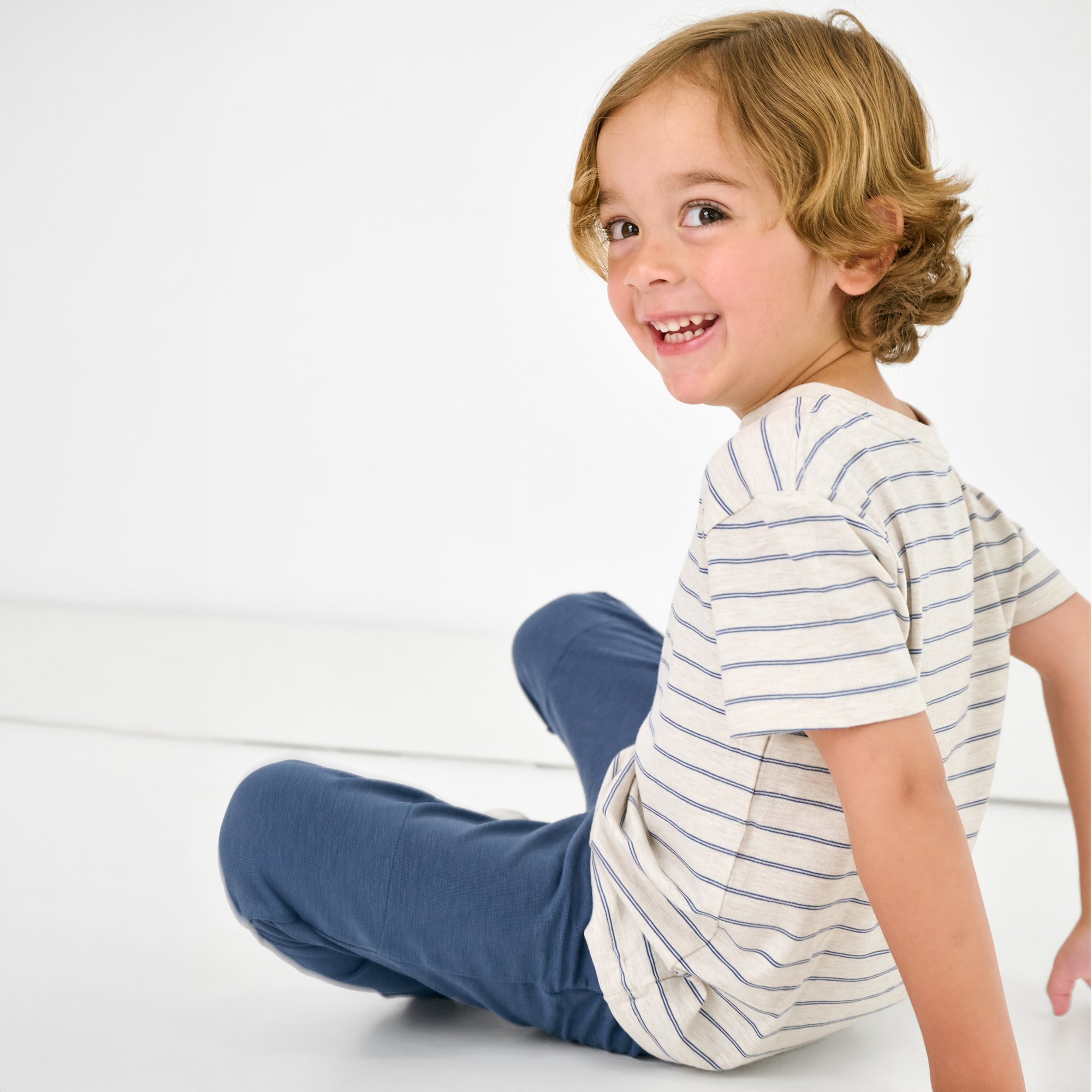 Sitting child wearing the Stone Stripes Short Sleeve Relaxed Tee with blue joggers