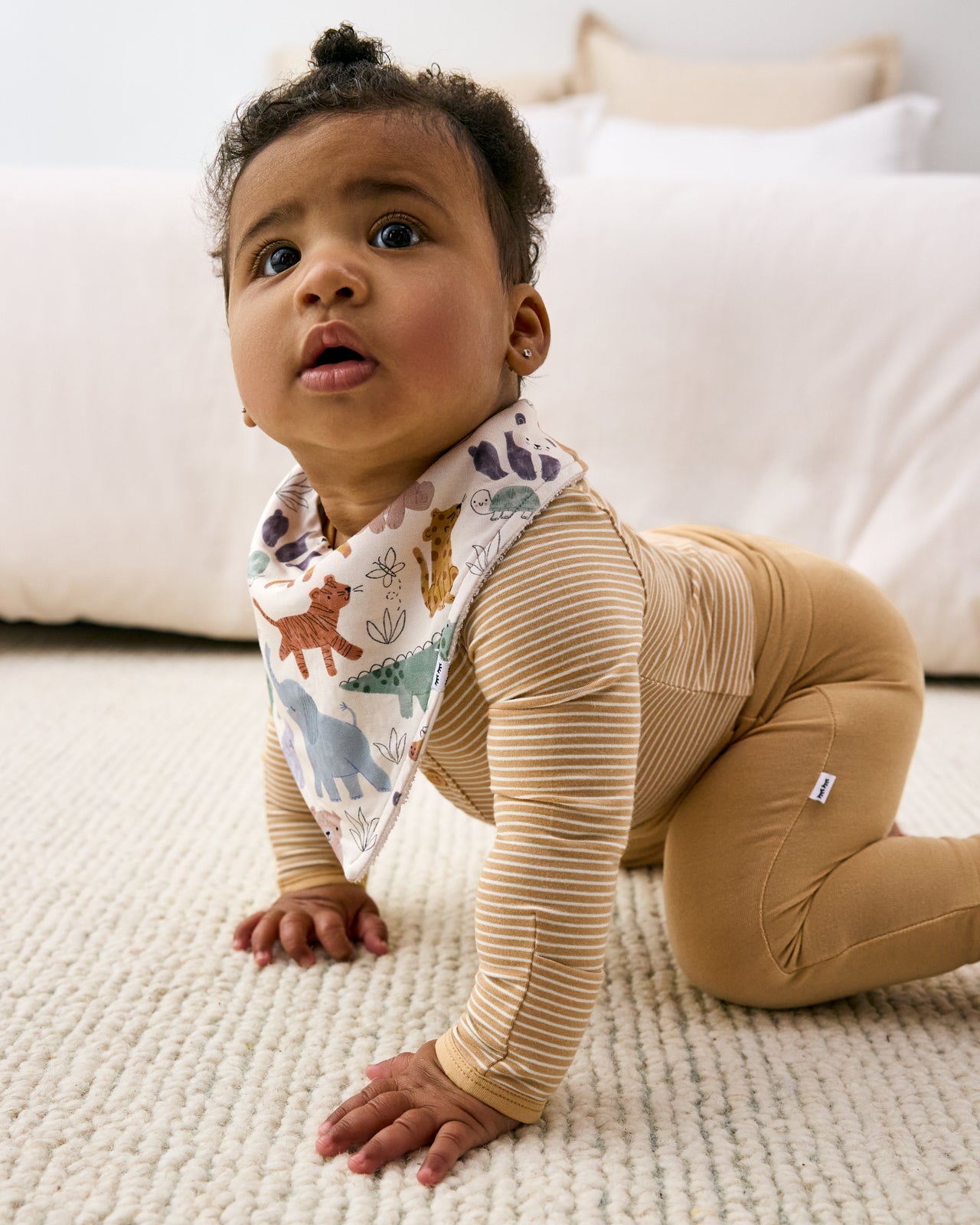 Crawling baby wearing the Sweet Safari Bandana Bib with a striped baby boysuit
