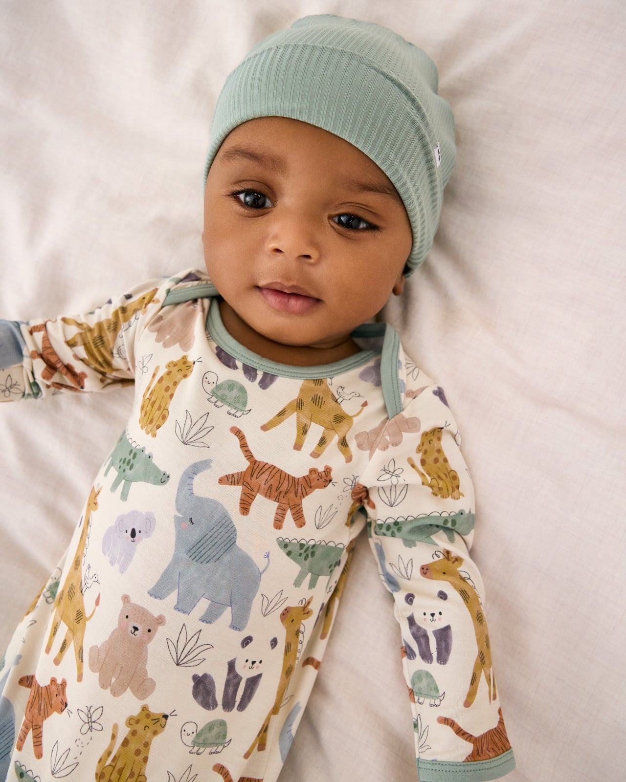Close up of baby wearing the Sweet Safari Infant Gown with a green baby beanie
