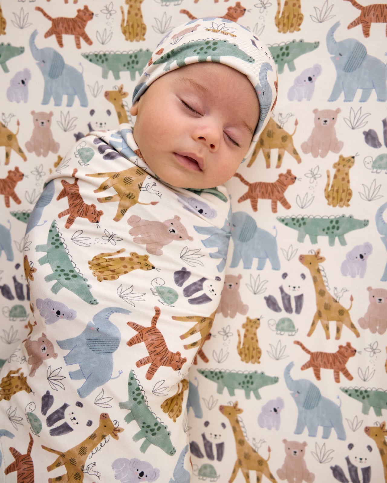 Aerial view of baby swaddled in the Sweet Safari Swaddle & Infant Beanie Set