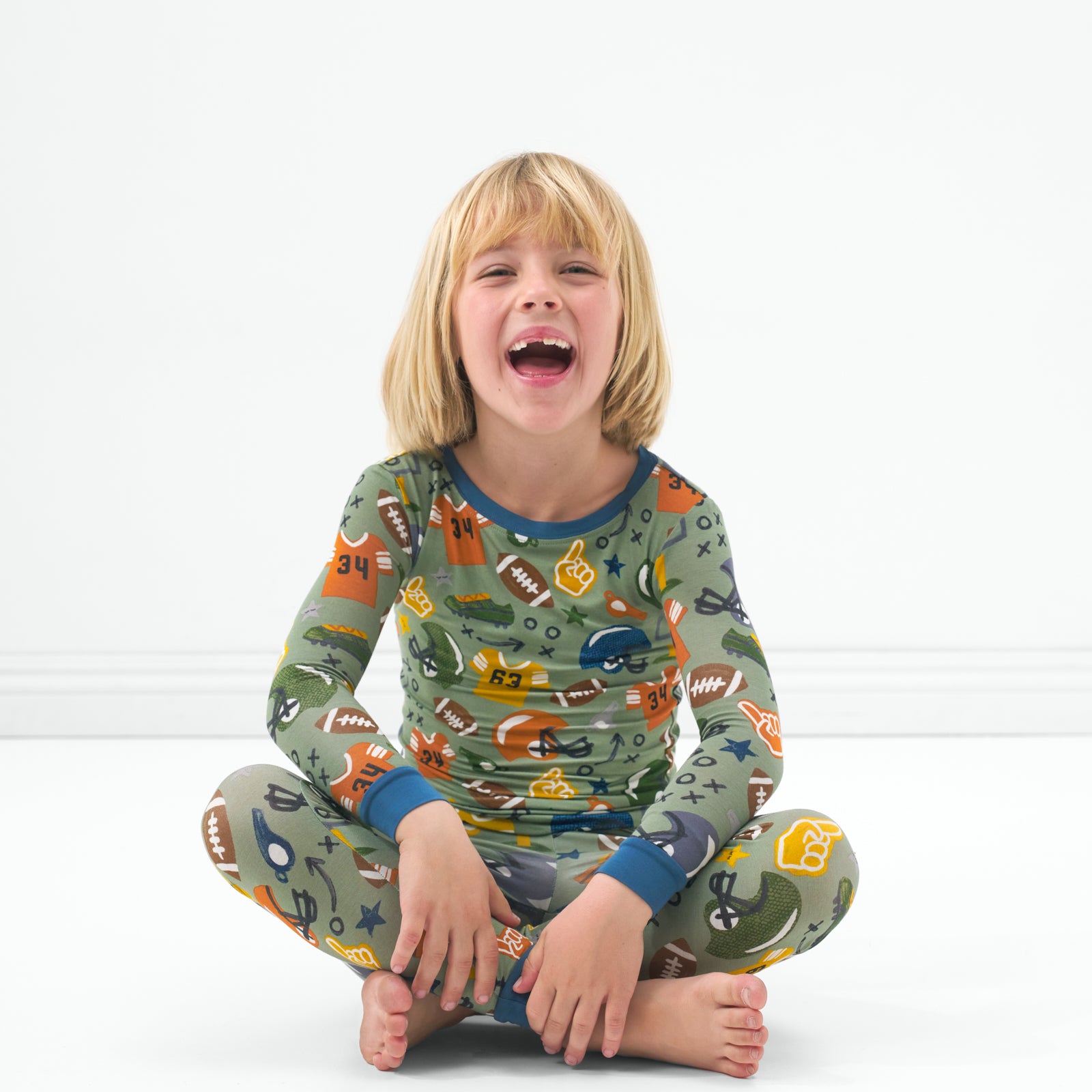 Sitting child wearing the Touchdown Time long sleeve pajama set