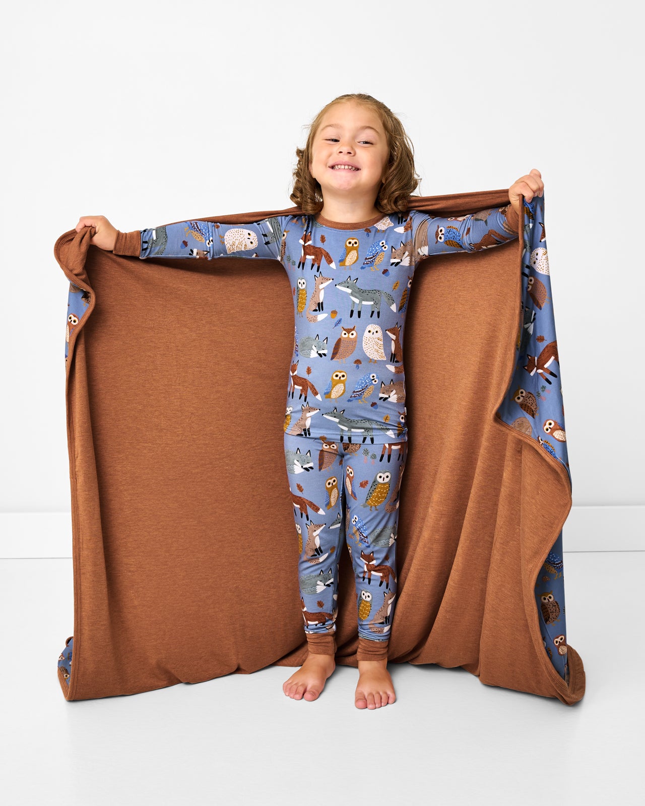 Standing girl holding up the Twilight Pals Large Cloud Blanket® showing the brown side