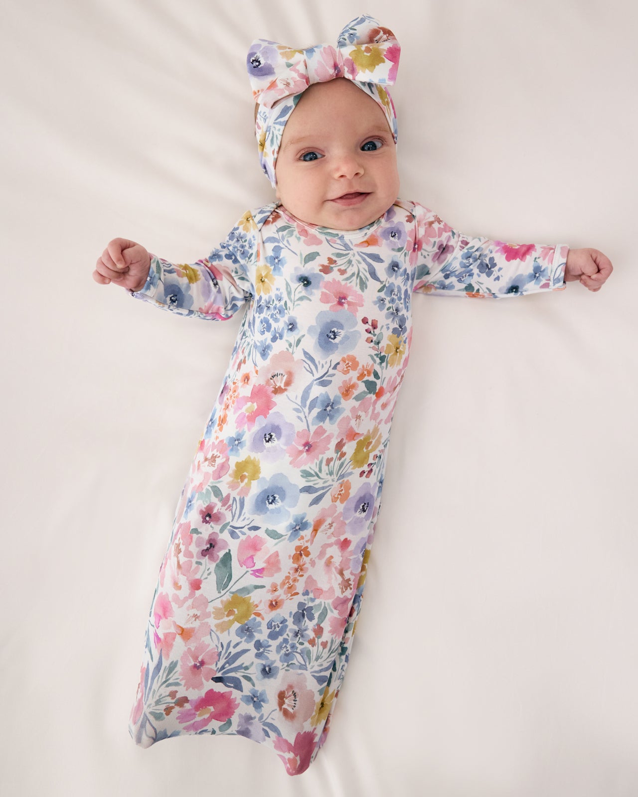 Aerial view of baby wearing the Tiny Blooms Infant Gown with a matching luxe bow headband