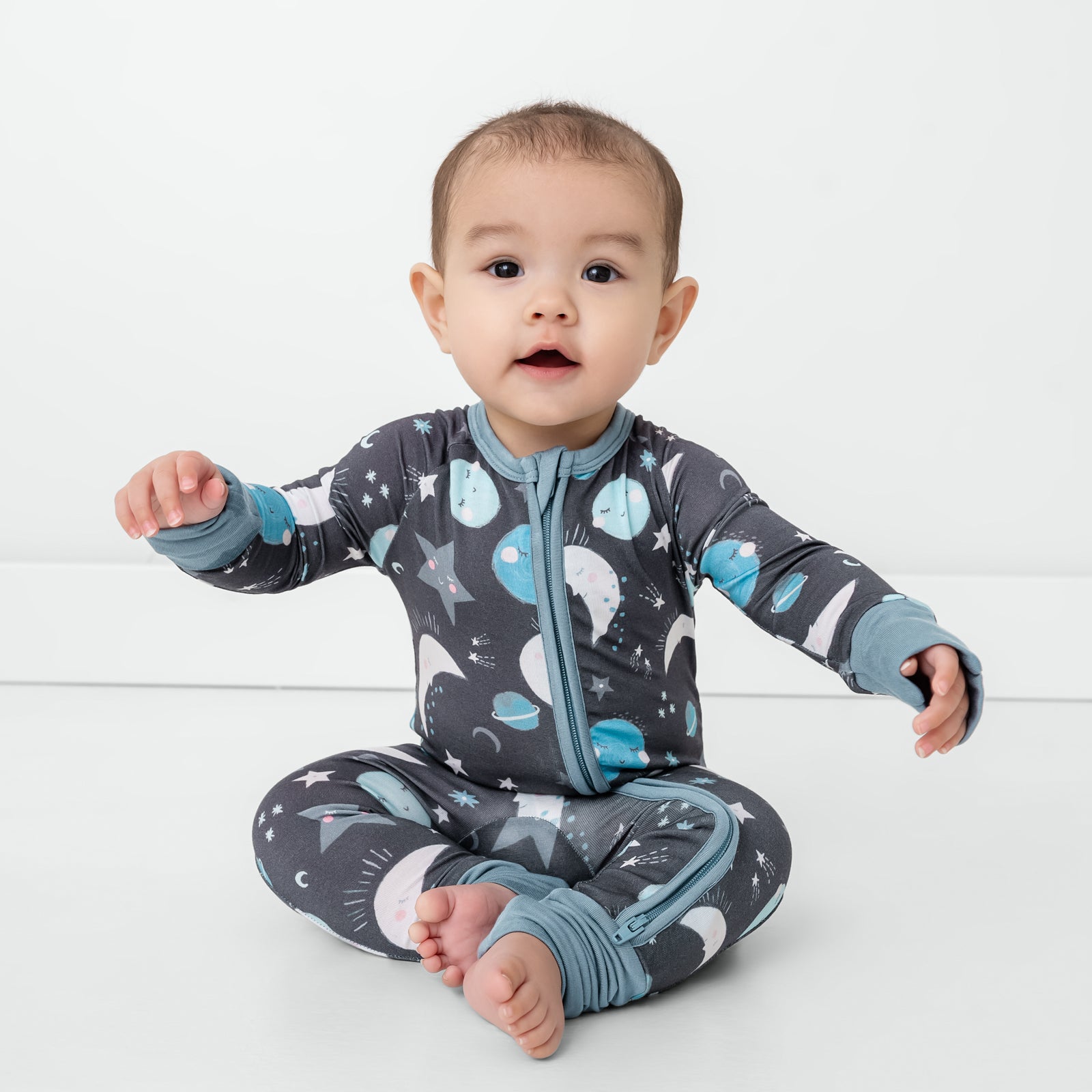 Sitting child wearing the Blue To the Moon & Back Zippy