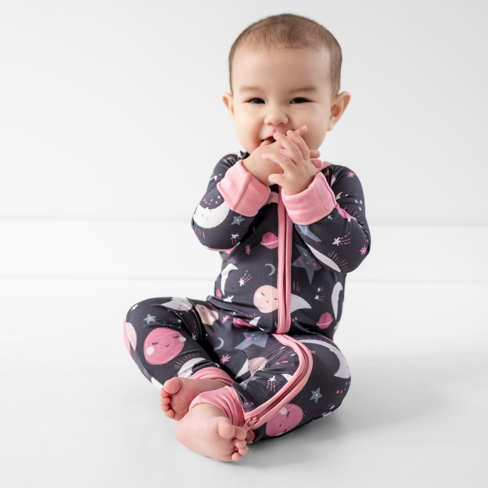 Sitting child wearing the Pink To the Moon & Back Zippy