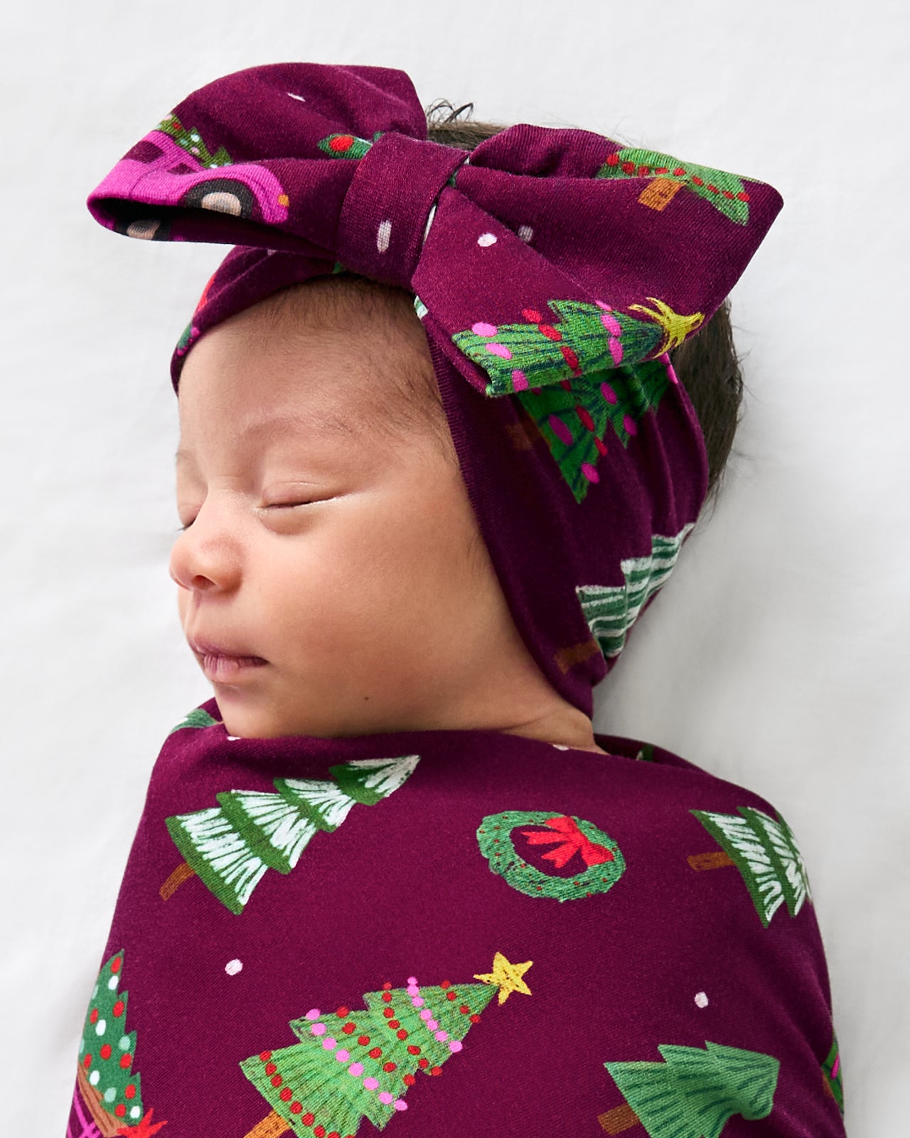 Close up of baby in the Cranberry Tree Traffic Swaddle & Luxe Bow Headband Set