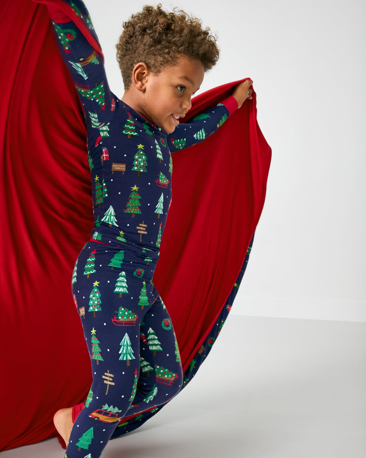 Child holding the Navy Tree Traffic Large Cloud Blanket® showing the solid red side