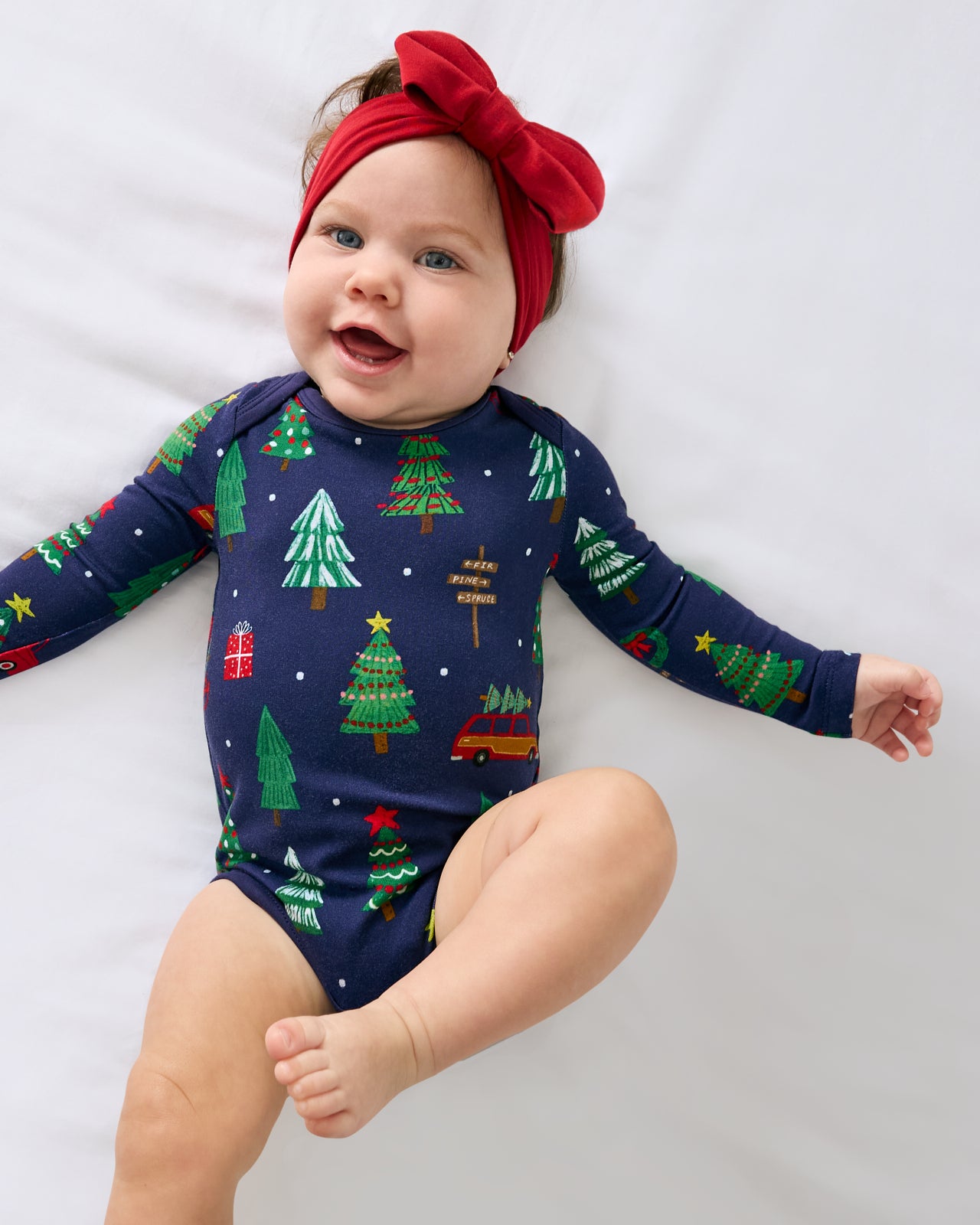 Ariel view of baby wearing the Navy Tree Traffic Bodysuit with a red luxe ow headband