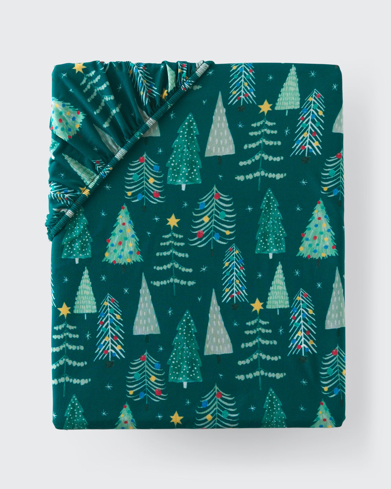 Flat lay of the Twinkling Trees Fitted Crib Sheet