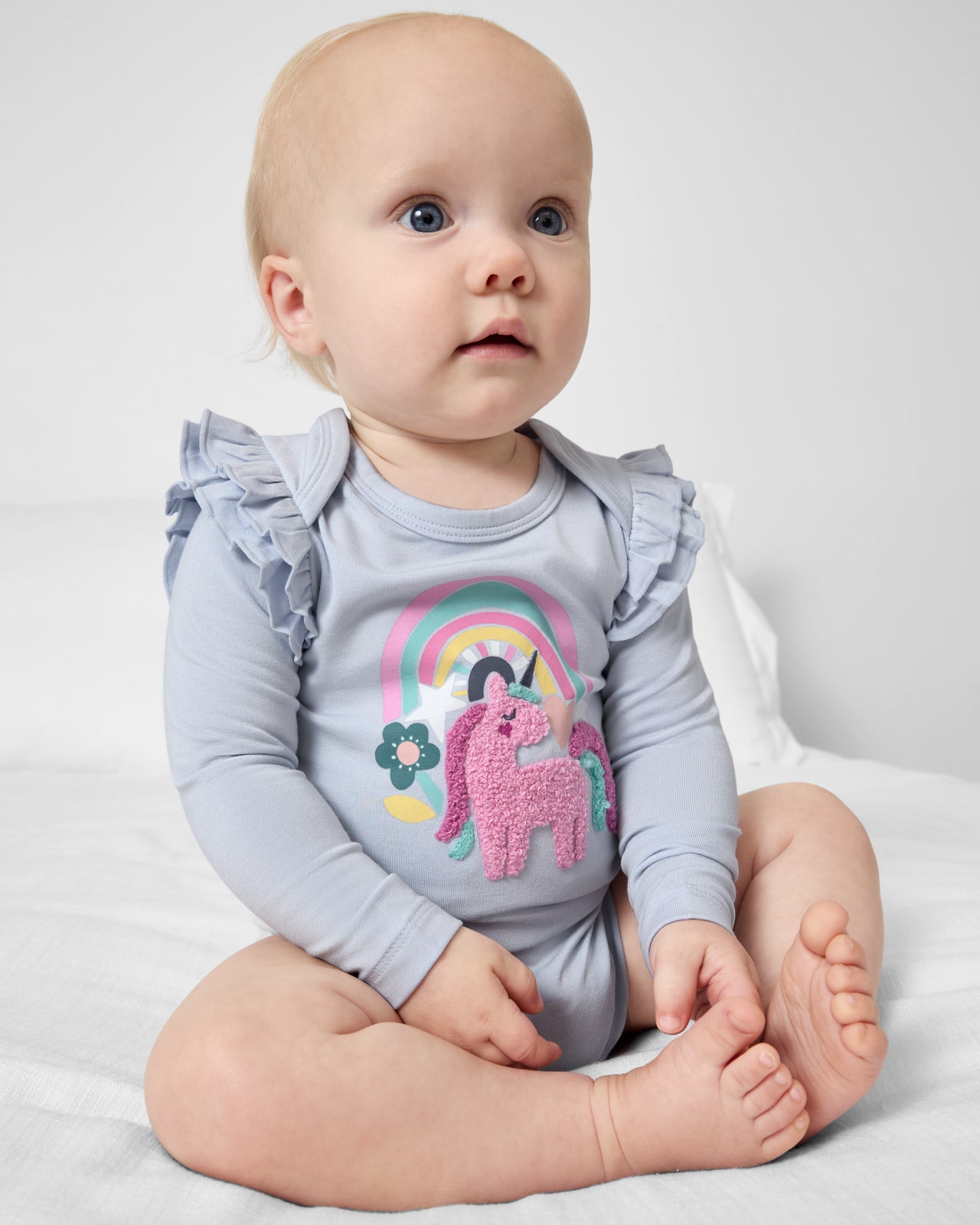 Sitting baby wearing the Unicorn Flutter Bodysuit
