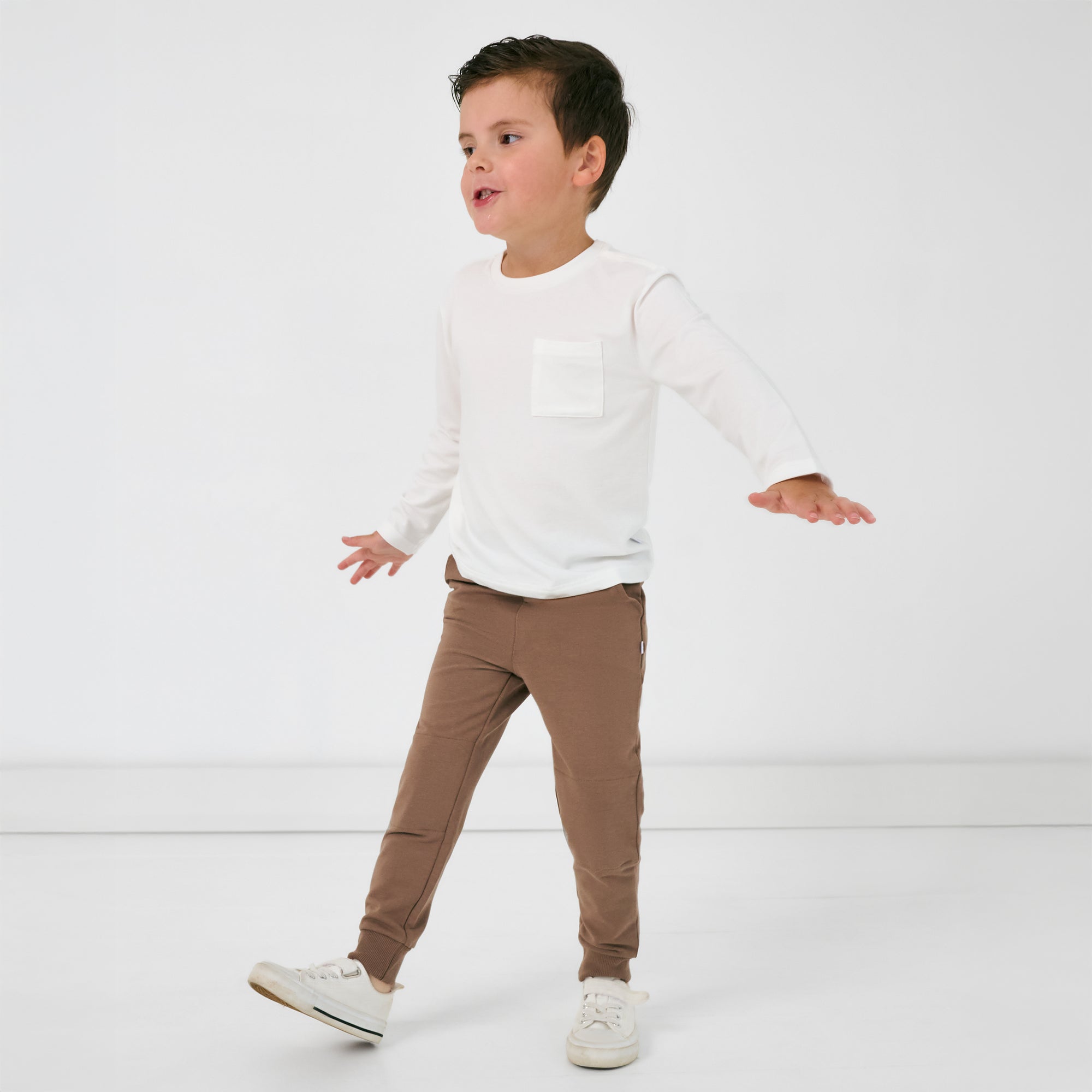 Walking child wearing the Vintage Brown Jogger and white long sleeve pocket tee