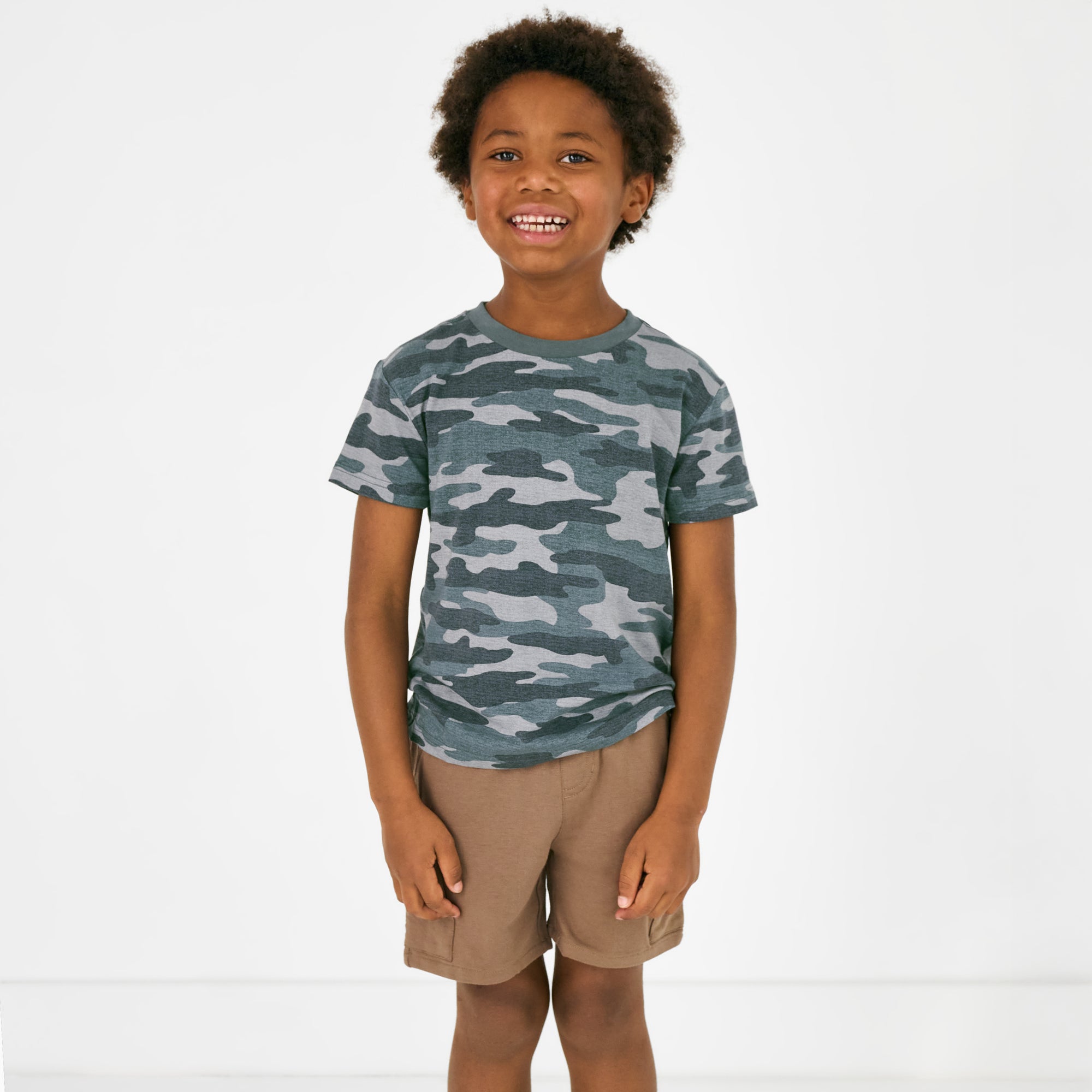 Standing child wearing the Vintage Camo Short Sleeve Relaxed Tee with vintage brown cargo shorts