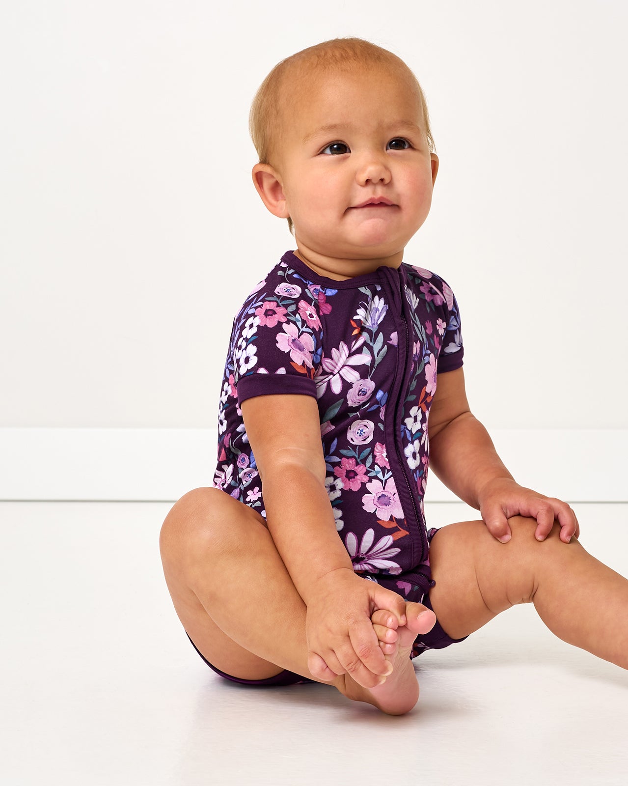 Sitting baby wearing the Violet Meadow Shorty Zippy