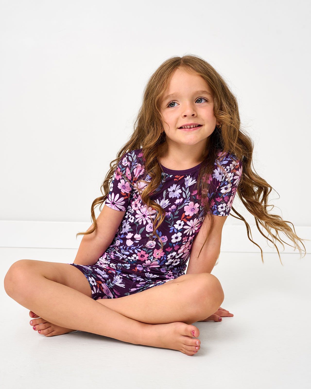 Sitting girl wearing the Violet Meadow Two-Piece Short Sleeve & Shorts Pajama Set