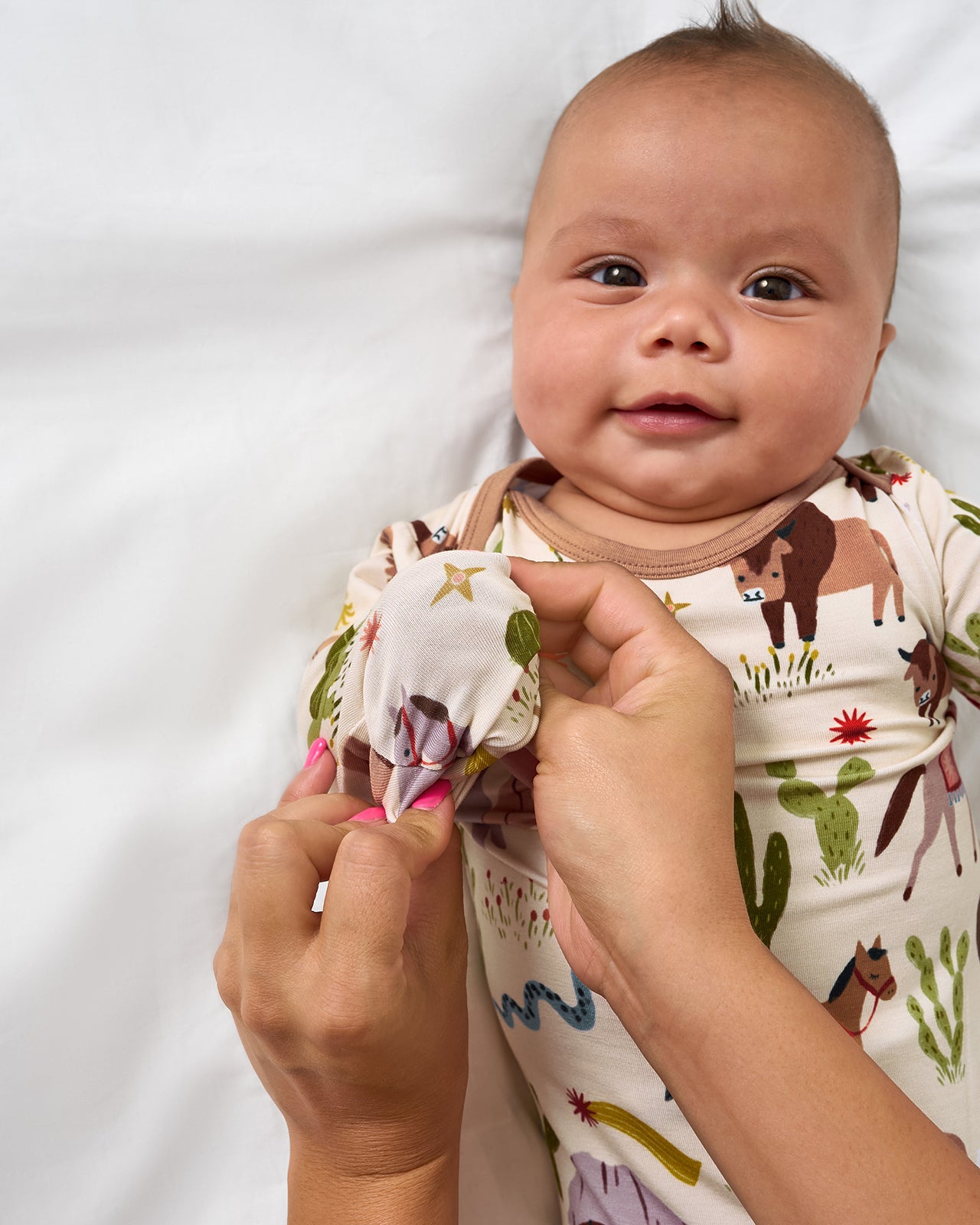 Adult demonstrating the mitten feature on the Wild Frontier Infant Gown