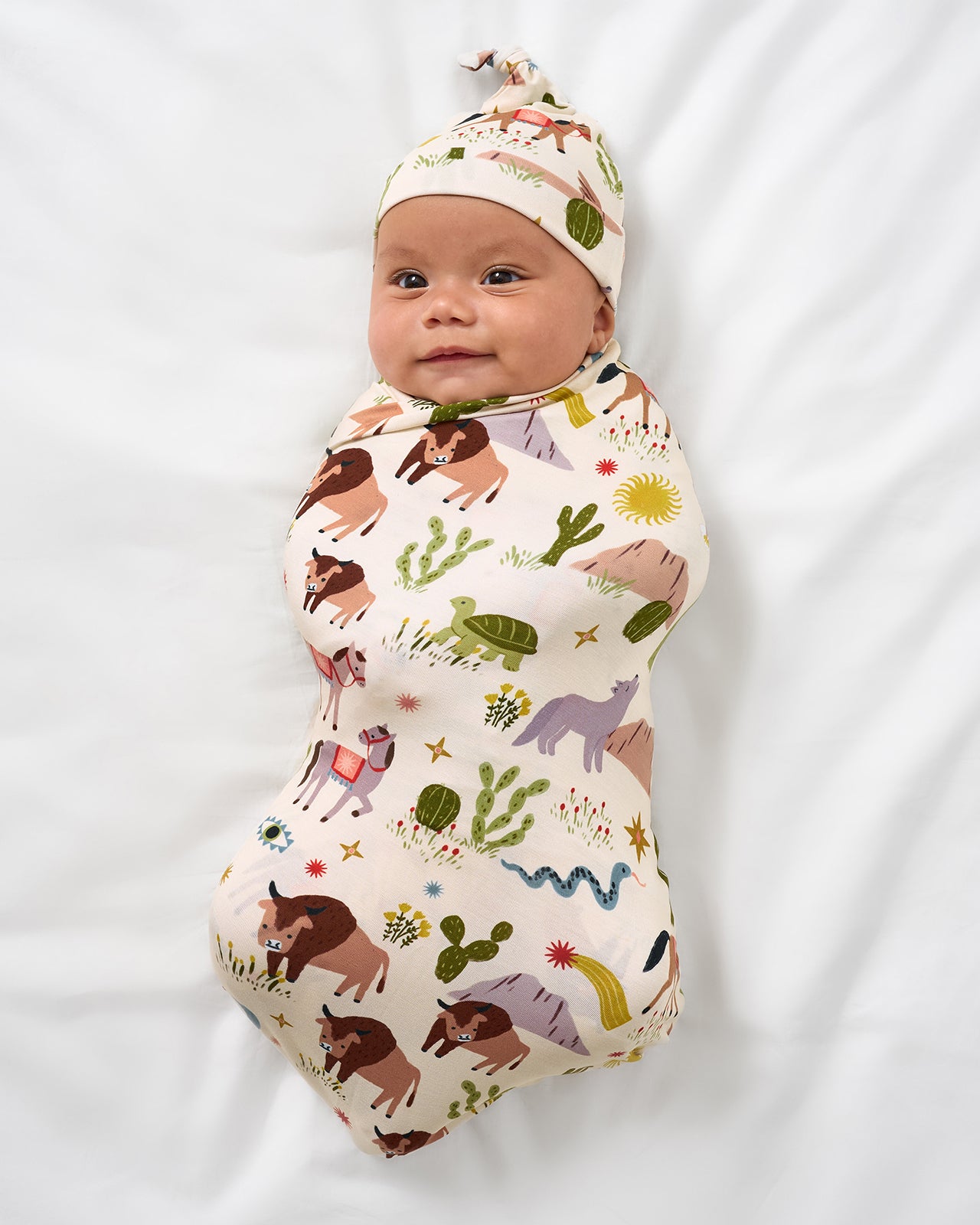 Aerial view of baby wearing the Wild Frontier Swaddle & Hat Set