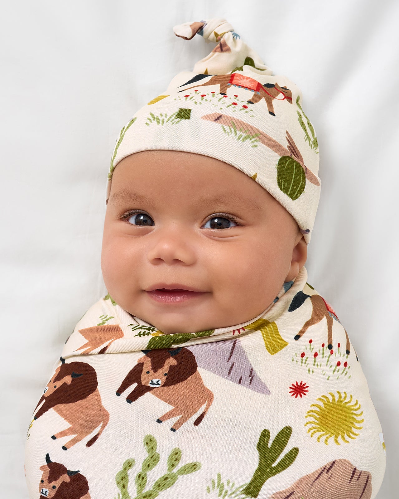 Close up of baby wearing the Wild Frontier Swaddle & Hat Set