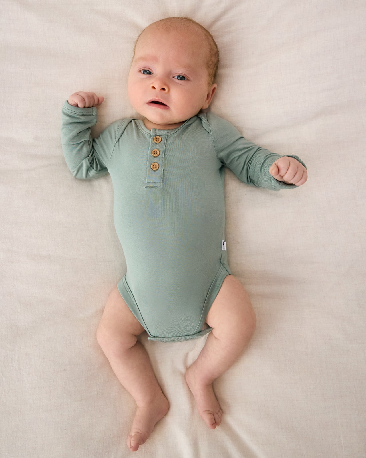 Aerial view of newborn wearing the Willow Henley Bodysuit