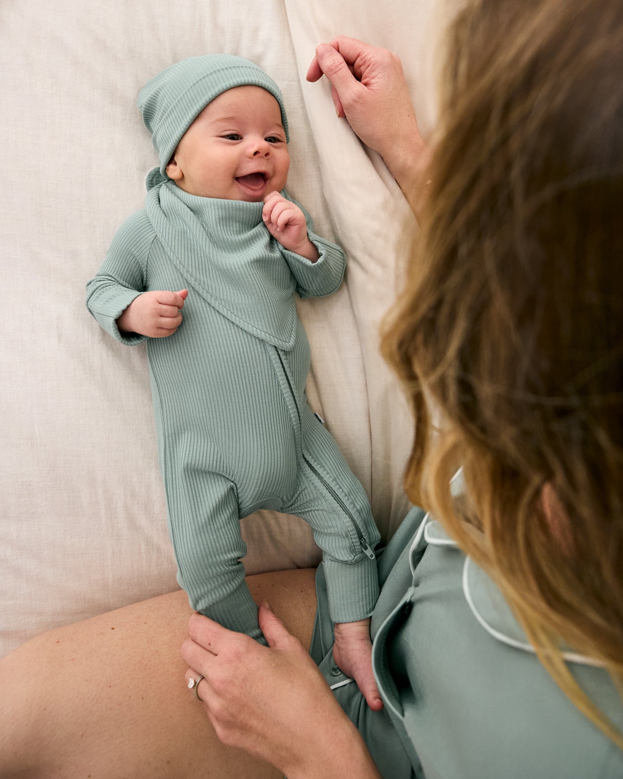 Baby wearing the Willow Ribbed Zippy with a matching green baby bib